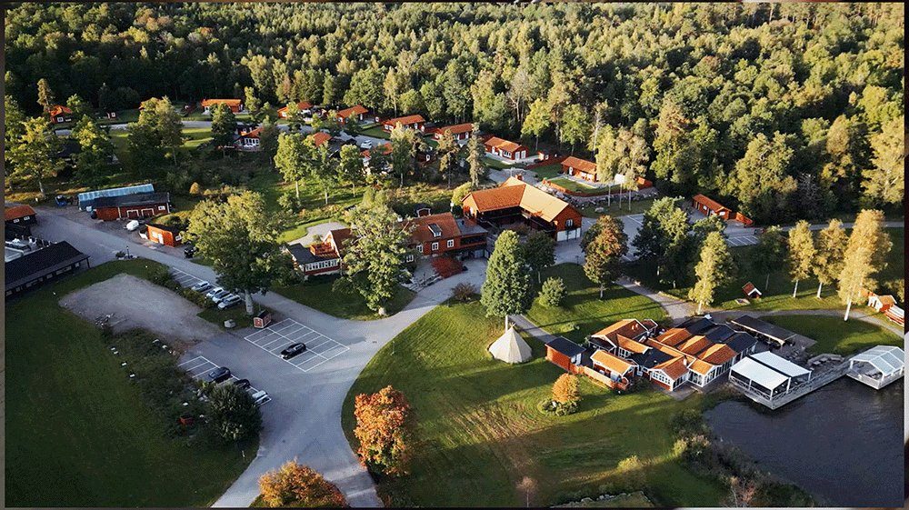 Flygfoto över resort med röda stugor vid sjö